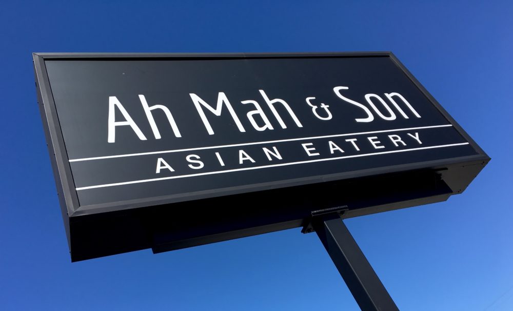 black sign against a clear blue sky with white letters that read Ah Mah and Son Asian Eatery in Crossville Tennessee