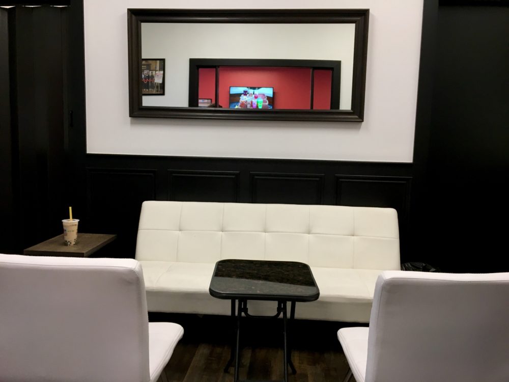 A sleek, modern boba tea lounge with black walls and white leather furniture at WIN Bubble Tea in Nashville, Tennessee
