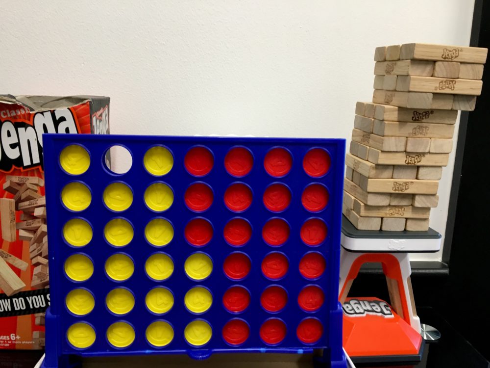 A plastic Connect 4 Game with blue frame and yellow and red playing pieces in the center. An orange box that reads JENGA is on the left, the wooden rectangular JENGA game pieces are on the right. This is the game lounge at WIN Bubble Tea in Nashville, Tennessee