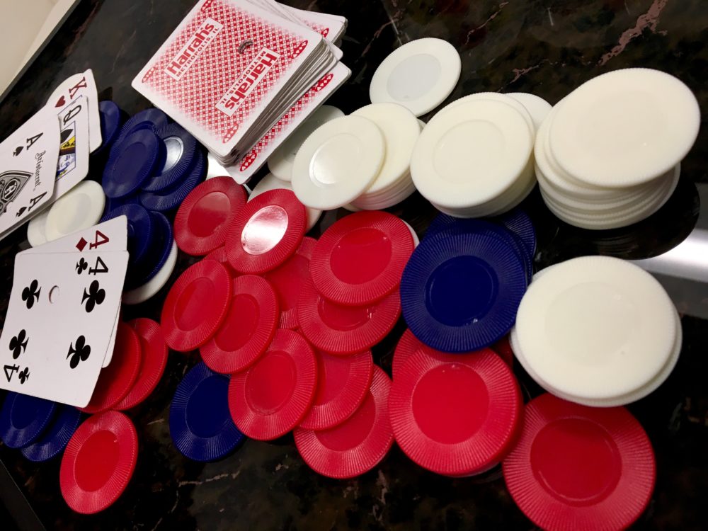 Red Harrah's Casino poker playing cards and red, white, and blue round poker chips spread across a black marble game table in the game lounge of WIN Bubble Tea in Nashville, Tennessee
