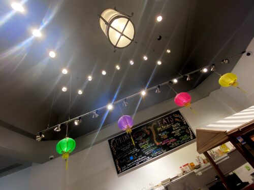 Bright ceiling lights, Green, Purple, Pink, and Yellow Asian lanterns and a black menu board for Bubble Tea at Coconut Whisk Cafe in Minneapolis Minnesota